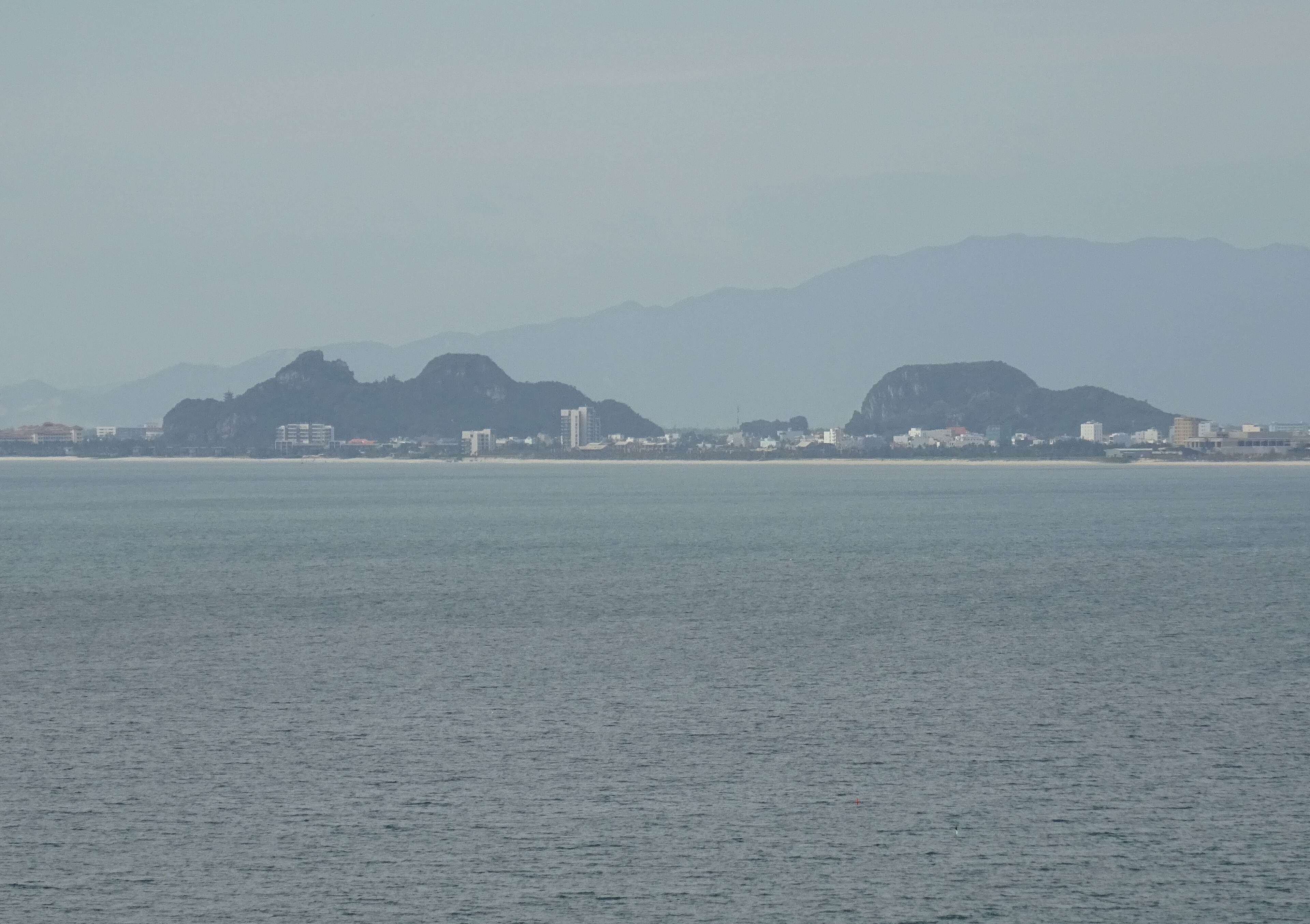 The Marble Mountains seen from across the bay, standing out from the flat coastline